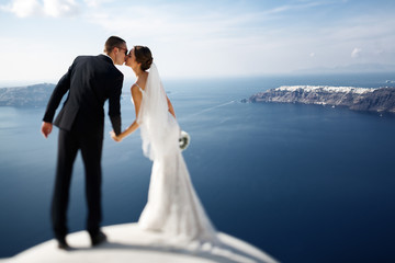Romantic beautiful couple kissing on terrace with sea, islands a