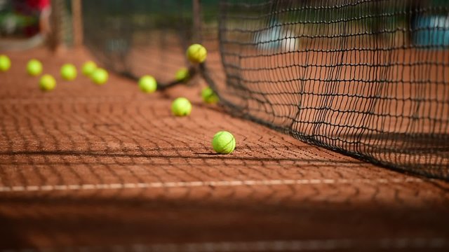 Tennis balls hitting the tennis net during practice game on a clay court
