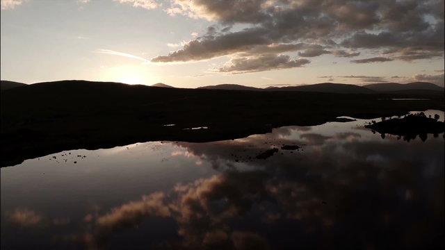 Aerial shot over Rannoch moor in Scotland revealing a desolute and baron landscape during sunset
