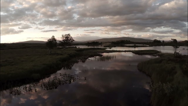 Aerial shot over Rannoch moor in Scotland revealing a desolute and baron landscape during sunset
