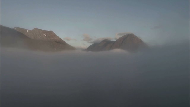 Aerial shot through cloud inversion revealing buachaille etive mor mountain during sunrise 
