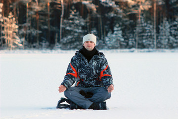 Fototapeta na wymiar yogi young man practices yoga and meditates on the snow in the winter