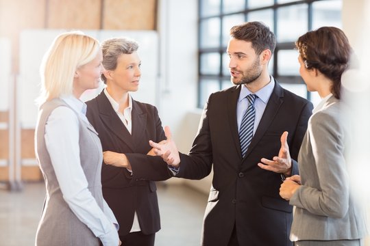 Business people discussing with each other while standing in office
