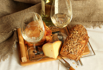 Two glasses with white wine, homemade bread and cheese..