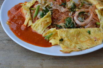 stir fried sukiyaki with seafood wrapped in egg and dressing sauce on dish