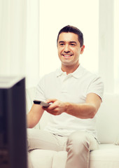 smiling man with remote control watching tv