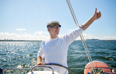 senior man at helm on boat or yacht sailing in sea