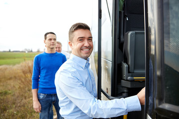 group of happy male passengers boarding travel bus