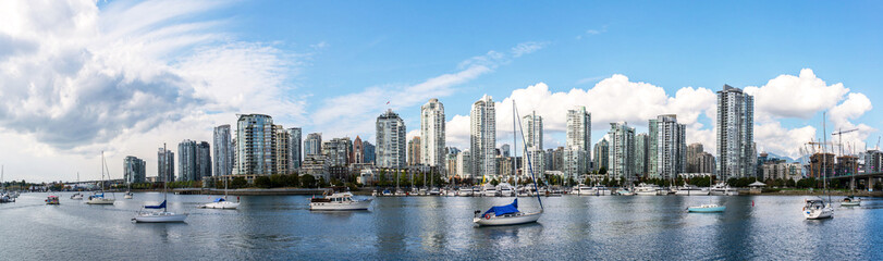 panoramic view of the buildings of vancouver city skyline behind a marina during a sunny day in british columbia in canada