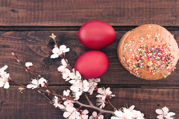 Obraz na płótnie Canvas Easter cake and red eggs on rustic wooden table. Top view