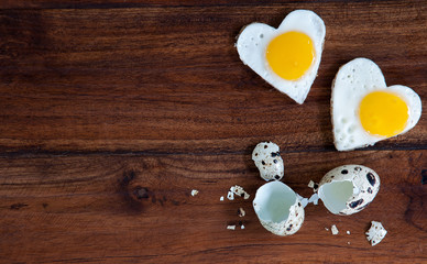 Two heart-shaped fried eggs on a wooden background