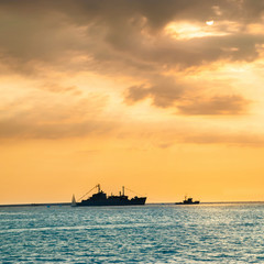 Sunset over blue sea with ship