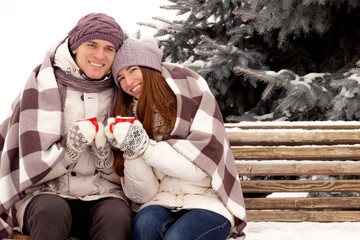 Happy couple in love with cup of coffee in park in winter