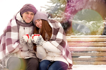 Happy couple in love with cup of coffee in park in winter with l