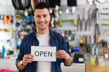 Bike shop owner holding open sign
