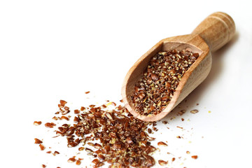 Ground flax seeds in wooden scoop on light background