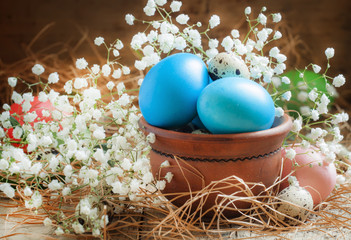 Blue colored Easter eggs and quail eggs in a clay bowl on the ol