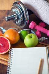 Diet plan. diet plan and a fruits and dumbbells lying on a wooden surface

