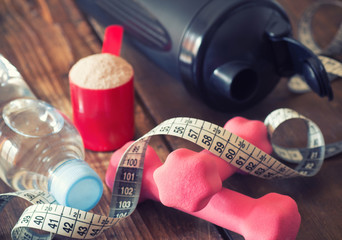 weight loss concept with tape measure whey powder, pink dumbbells and black shaker