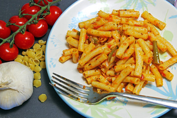 Overhead view of cooked mini Ziti pasta with tomato gravy, tomatoes and garlic.