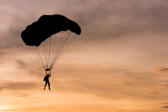 Silhouette of parachute and airplane on sunset background