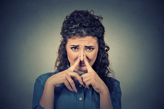 woman pinches nose with fingers looks with disgust something stinks bad smell