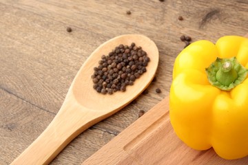 Yellow bell pepper black pepper on wooden spoon