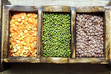 Different kinds of lentils in a wooden box.