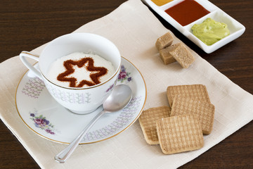 Il cappuccino decorato,con vicino le marmellate e i biscotti