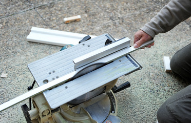 Carpenter cutting a ribbon of white wood