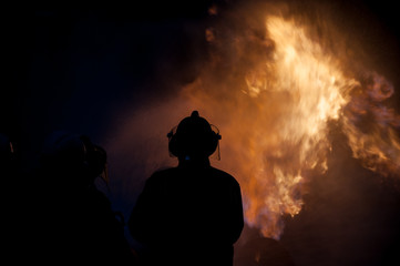 Silhouette of Firemen fighting a raging fire with huge flames of burning timber