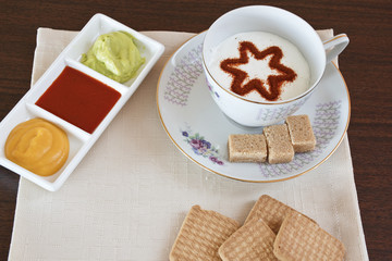 Il cappuccino decorato,con vicino le marmellate e i biscotti