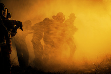 Silhouette of Firemen fighting a raging fire with huge flames of burning timber