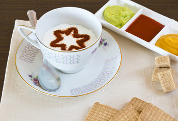 Il cappuccino decorato,con vicino le marmellate e i biscotti