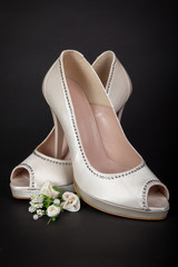 Elegant white female shoes on dark background. Bride shoes