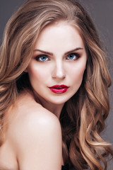 Fototapeta premium Portrait of wonderful young blonde woman with long hair looking at camera, smiling
