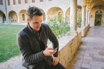 Young man sitting who is using the phone