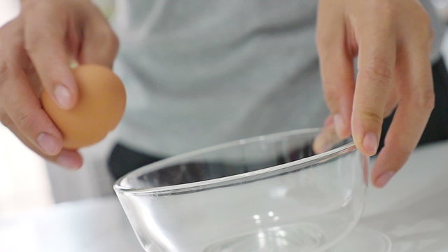 Woman cracking eggs in the kitchen, Slow motion shot
