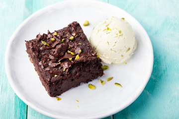 Chocolate brownie, cake on a white plate on a turquoise wooden background
