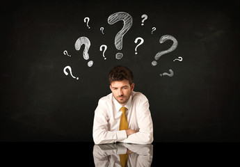 Sitting businessman under question marks