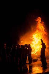 Silhouette of Firemen fighting a raging fire with huge flames of burning timber