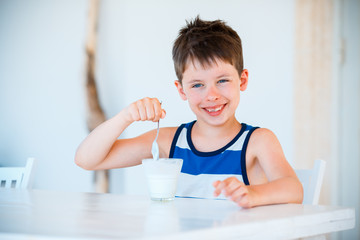 Smiling little boy eating delicious yogurt