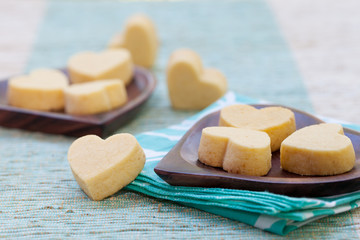 Handmade heart shape cookies on wooden plate and blue napkin Outdoor background Frangipani flower 