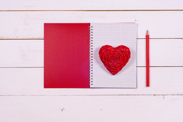 Notebook and heart on a white rustic background. Valentine's Day. Top view. Space for text.
