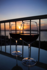 Two glasses with red wine in sunset