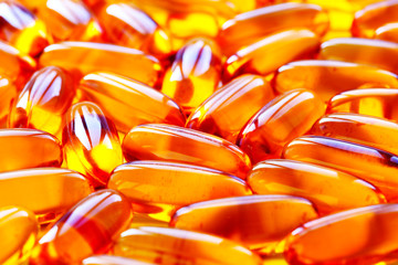 Biological additives to food, vitamins for a healthy lifestyle, capsules an omega 3 with cod-liver oil, transparent orange color an embankment on a light background close up
