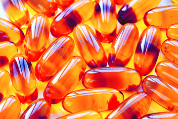 Biological additives to food, vitamins for a healthy lifestyle, capsules an omega 3 with cod-liver oil, transparent orange color an embankment on a light background close up