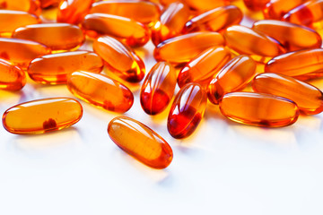 Biological additives to food, vitamins for a healthy lifestyle, capsules an omega 3 with cod-liver oil, transparent orange color an embankment on a light background close up