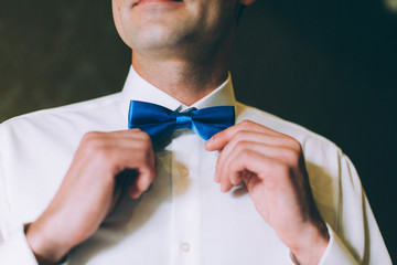 Fashion photo of a man with beard correcting his bowtie