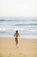 Fototapeta na wymiar Mujer en bikini caminando por una playa del Algarve